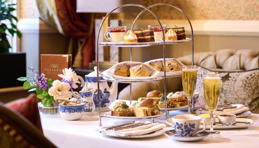 Afternoon Tea pictured in our Mezzanine with two glasses of bubbly prosecco with some sweet and savoury treats on a three tier plate
